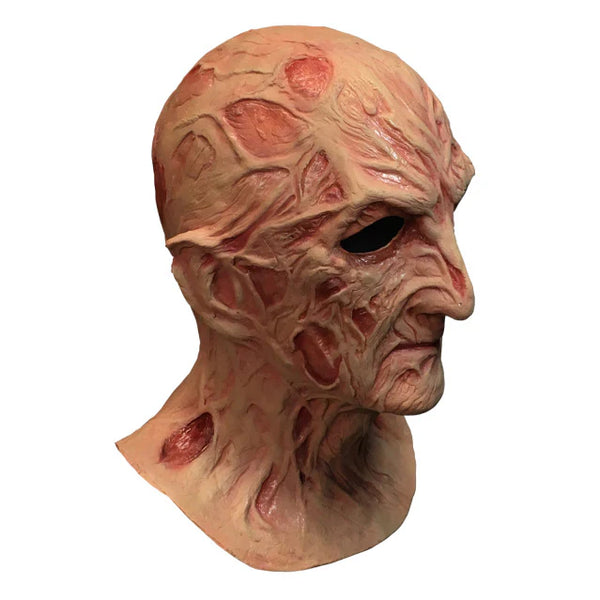 A Nightmare on Elm Street Dream Master Freddy Krueger Deluxe Costume Mask Features a latex full‑coverage sculpt with heavily burned, blistered skin textures, deep scar grooves, and warped facial contours, finished in mottled flesh tones with dark red shading to emphasize rot and damage and distortion that reflects Freddy’s supernatural decay, right profile