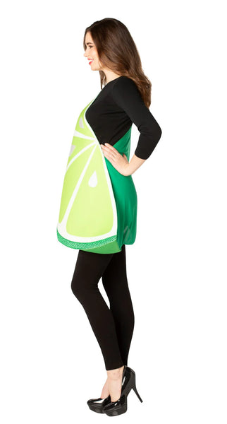 Side view of Woman posing in the Adults Lime Slice Costume Featuring a foam-style tunic designed in a large half-circle lime slice shape, with a bright green outer rind, lighter green interior segments, white dividing lines, and printed juice droplet details