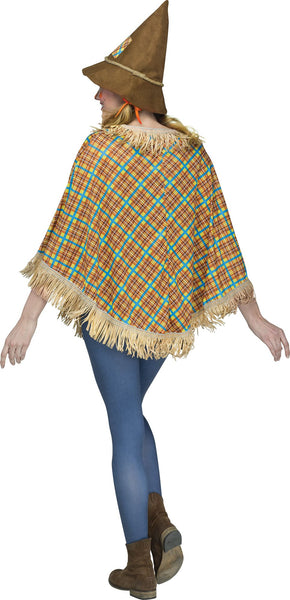 Back view of a woman modeling the Adults Sweet Scarecrow Costume Poncho featuring a loose, easy‑to‑wear poncho‑style top designed in a colorful plaid pattern with warm fall tones of orange, yellow, blue, and brown; accented with stitched patchwork details in contrasting fabrics and layered straw‑style fringe trim along the neckline, sleeves, and bottom hem for a classic scarecrow look