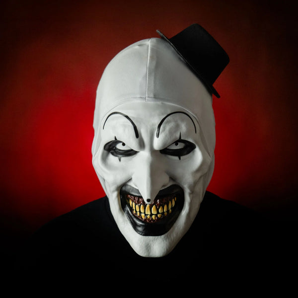 Art Terrifier Art the Clown Deluxe Injection Costume Mask of white clown face with black makeup detail and white headcover with attached black hat, cinematic image with red background
