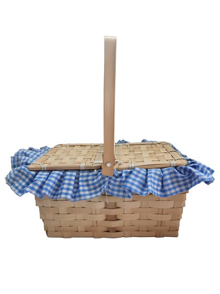 Boots and Brother's Puppy in a Basket featuring a woven natural wood basket with a handle, lined with a blue and white gingham fabric ruffle, handle up, closed, side view