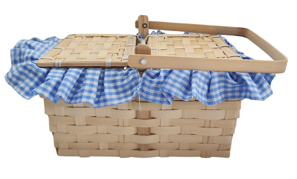 Boots and Brother's Puppy in a Basket featuring a woven natural wood basket with a handle, lined with a blue and white gingham fabric ruffle, closed, side view