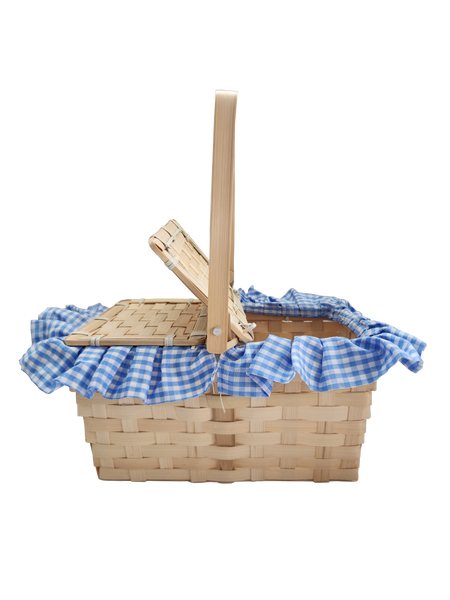 Boots and Brother's Puppy in a Basket featuring a woven natural wood basket with a handle, lined with a blue and white gingham fabric ruffle, open, handle up, side view