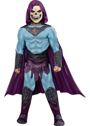 Child in the Boys Deluxe Masters Of The Universe Skeletor Costume Featuring a full costume set including a blue jumpsuit with printed muscle shading throughout the chest, arms, and legs, a molded chest armor piece with intricate dark detailing and a red gem centerpiece, a matching belt with sculpted accents, attached boot tops, long wrist gauntlets, a flowing purple hooded cape, and a full-face skull mask with defined teeth and hollow eye details.