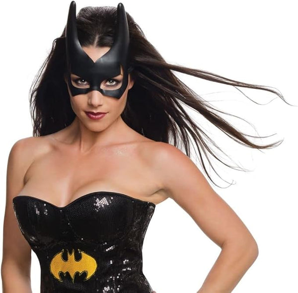 Woman modeling the Batgirl mask featuring a sleek molded black half‑face mask crafted from smooth plastic, designed with tall, sharply pointed bat ears that extend upward for a dramatic silhouette; includes cleanly cut eye openings and subtle contouring around the nose bridge and brow for a snug, structured fit. The mask is finished with elastic side straps that secure around the head, maintaining the classic Batgirl shape while keeping the design simple and bold