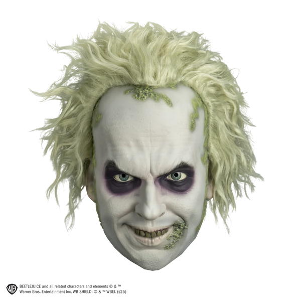 Deluxe Beetlejuice Injection Costume Mask features a gnarly yellow‑green complexion, pale, white cheeks and complexion, a wide crooked grin packed with uneven, decayed yellow teeth, eyes rimmed with dark purple bags and shading, heavy wrinkle lines across the brow and mouth, and moss like details along the side of the mouth and hairline with matching wild, frizzy green hair attached, front view