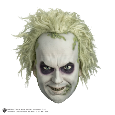 Deluxe Beetlejuice Injection Costume Mask features a gnarly yellow‑green complexion, pale, white cheeks and complexion, a wide crooked grin packed with uneven, decayed yellow teeth, eyes rimmed with dark purple bags and shading, heavy wrinkle lines across the brow and mouth, and moss like details along the side of the mouth and hairline with matching wild, frizzy green hair attached, front view