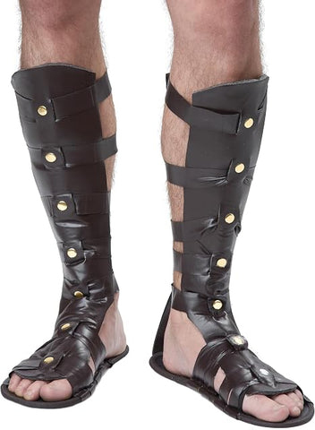 Deluxe Roman or Greek Gladiator Costume Sandals Featuring a pair of brown faux leather-style gladiator sandals designed with multiple horizontal straps across the foot and calf, extended knee-high panels with cutout openings, round gold-tone stud accents along the sides, an open-toe design, and a flat sole base