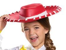 Girl show the hat in the Girls Disney Pixar Toy Story Cowgirl Jessie Costume Featuring a one-piece jumpsuit designed with a white top and bright yellow sleeve cuffs, this costume includes printed button details and a wide brown belt graphic with a gold buckle at the waist. The attached pants feature a blue upper section that transitions into a white base with black cow-print panels and flared leg openings, paired with a red wide-brim hat accented with white stitching detail around the edge.