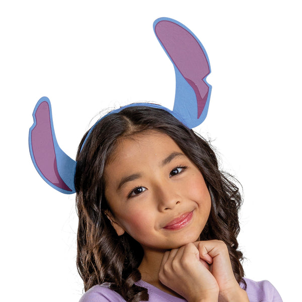 Girl posing in the Girls Disney's Lilo & Stitch Tutu and Headband Costume Accessory Kit featuring a two‑piece, including a layered blue tulle tutu skirt and a coordinating headband with oversized Stitch ears. The skirt is designed with multiple ruffled tiers of soft mesh fabric, accented with printed floral patterns and a glittery purple elastic waistband. A small Stitch character medallion sits at the front of the waistband. The headband features large blue ears with pink inner panels. 