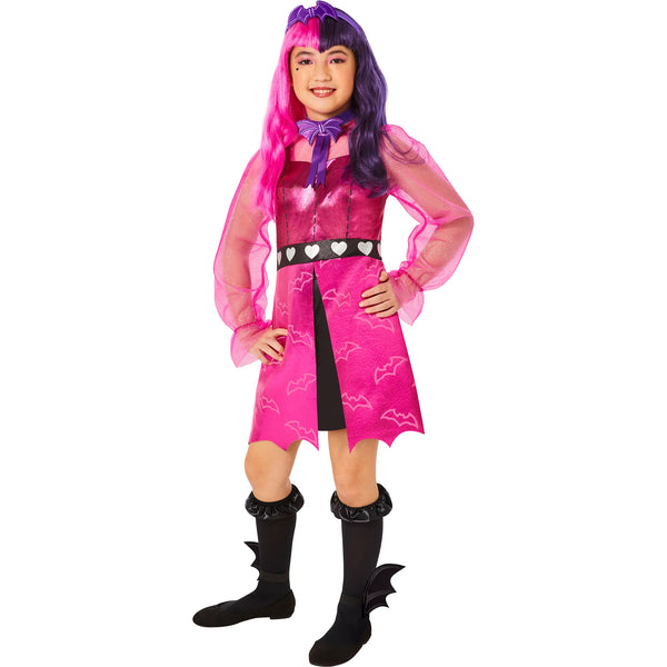 Girl posing in the Girls Monster High Draculara Costume Featuring a pink dress with a metallic sheen and bat print pattern on the skirt, designed with a fitted bodice, sheer long sleeves, and a black waistband accented with heart details, paired with a bat-shaped bow tie, a matching headpiece with bat-inspired design, black knee-high socks, and ankle accessories shaped like bat wings.