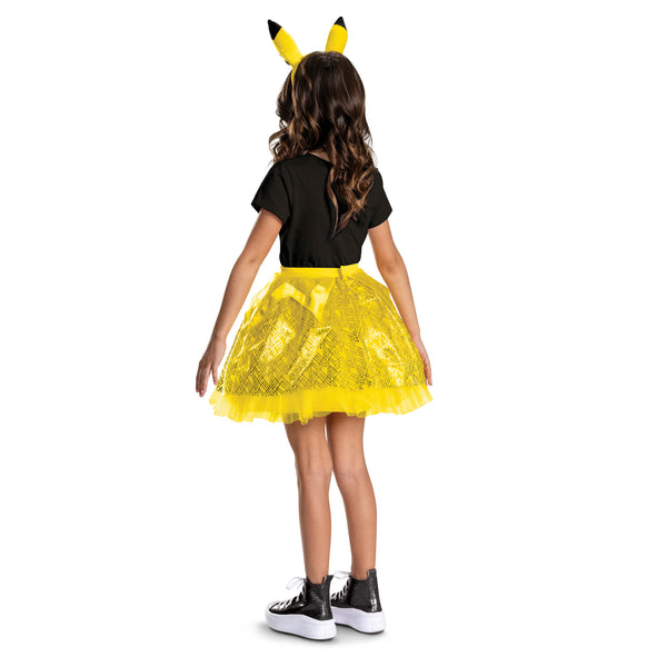 Girl posing in the Nintendo Pokemon Pikachu Tutu and Headband Kit featuring a bright two‑piece set that includes a layered yellow tutu skirt and a matching headband with Pikachu ears. The tutu is designed with multiple layers of soft yellow mesh and tulle, accented with gold geometric patterns and subtle sparkle details, along with a satin waistband finished with a small Pikachu character medallion at the front. The headband features tall, upright Pikachu ears in vibrant yellow with black tips and Pikachu