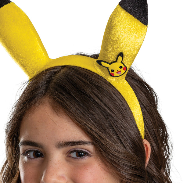 Girls in the Nintendo Pokemon Pikachu Tutu and Headband Kit featuring a bright two‑piece set that includes a layered yellow tutu skirt and a matching headband with Pikachu ears. The tutu is designed with multiple layers of soft yellow mesh and tulle, accented with gold geometric patterns and subtle sparkle details, along with a satin waistband finished with a small Pikachu character medallion at the front. The headband features tall, upright Pikachu ears in vibrant yellow with black tips and Pikachu