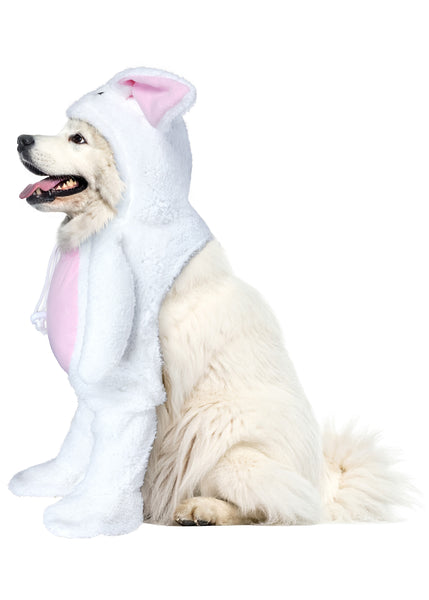 Side of Great Pyrenees wearing Pets Walking Bunny Rabbit Costume featuring  a plush, full‑body white bunny outfit designed with a clever “walking” illusion that makes it appear as though the rabbit itself is standing upright; styled with soft white faux‑fur fabric, long floppy ears lined in light pink, and an attached bunny headpiece with embroidered facial details. The costume includes stuffed faux arms that extend outward holding a bright orange carrot prop, along with a rounded pink belly