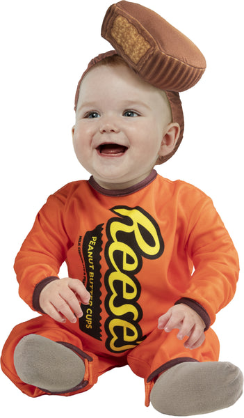 Baby wearing the Reese's Peanut Butter Cup costume featuring a bright orange one‑piece jumpsuit styled to look like a classic Reese’s package, printed with bold yellow and black “Reese’s” lettering across the front along with a vertical “Peanut Butter Cups” graphic panel; designed with long sleeves and brown trim accents at the cuffs. The look is completed with a soft plush Reese’s peanut butter cup headpiece, shaped like the iconic chocolate treat