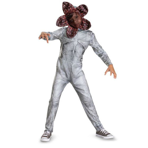 Child posing in the Kids/Teens Stranger Things Demogorgon Costume Featuring a full-length gray jumpsuit with printed texture detailing designed to resemble the Demogorgon’s skin, this unisex costume includes long sleeves and a fitted silhouette with subtle patterning throughout the front and back. The set is paired with a character headpiece designed with a flower-like opening structure, featuring multiple petal-shaped sections with printed red interior detailing and layered graphic elements.