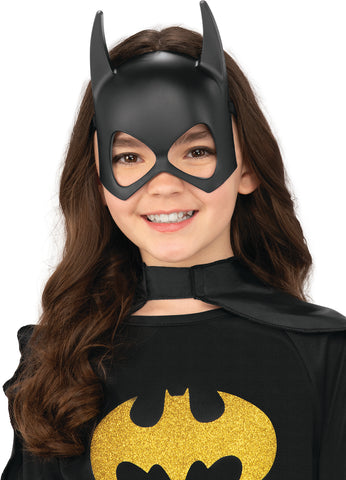 Girl wearing the DC Universe Batgirl Mask featuring  a molded black half‑face mask crafted from smooth, lightweight plastic, designed with Batgirl’s signature pointed bat ears extending upward from the top of the mask; styled with clean, angular eye openings and a gently contoured nose bridge for a snug, heroic fit. The matte black finish creates a sleek, uniform appearance, instantly capturing the recognizable Batgirl silhouette from the DC Universe