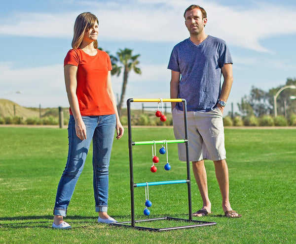 Two people standing on grass with a ladder ball game.