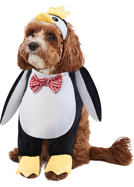 Cockapoo dog modeling the Pets Walking Penguin Costume which features a plush, full‑body penguin "walking" illusion in classic black‑and‑white coloring with a soft white belly panel, black flipper‑style sides, and oversized yellow plush feet and an attached penguin character hood with embroidered eyes, a soft yellow beak, and a bright yellow crown perched on top, along with a red‑and‑white checkered bow tie