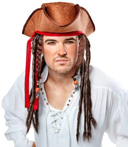 Man wearing Pirate Hat with Dreads Costume Hat featuring a weathered brown tricorn‑style pirate hat with a textured, leather‑look finish and stitched edging along the brim; accented with a wrapped red fabric band tied around the hat, from which long dark brown faux dreadlocks hang down on both sides; several of the dreadlocks are decorated with small bead details in metallic silver and amber tones, front view