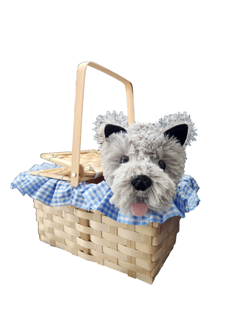 Boots and Brother's Puppy in a Basket featuring a woven natural wood basket with a handle, lined with a blue and white gingham fabric ruffle, holding a plush dog toy with gray and white fur, black ears, and a pink tongue