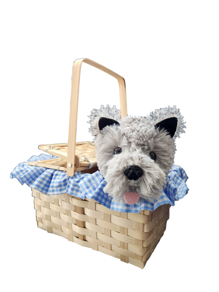 Boots and Brother's Puppy in a Basket featuring a woven natural wood basket with a handle, lined with a blue and white gingham fabric ruffle, holding a plush dog toy with gray and white fur, black ears, and a pink tongue
