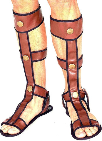 Man wearing Roman or Greek Gladiator Costume Sandals which feature a pair of brown leather‑look shin‑high sandal covers designed to recreate traditional ancient‑era gladiator footwear; styled with a vertical front strap running from the toes up the shin, secured with horizontal wrap straps and accented by round gold‑tone stud details at key connection points; finished with black trim outlining each strap and an open‑toe sandal base that completes the classic Roman silhouette