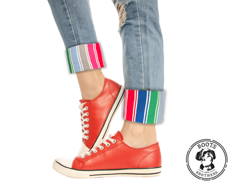 Red sneakers with colorful rolled-up jeans and rainbow striped good guys Chucky cosplay pants cuffs on a white background, featuring the Boots & Brothers logo.