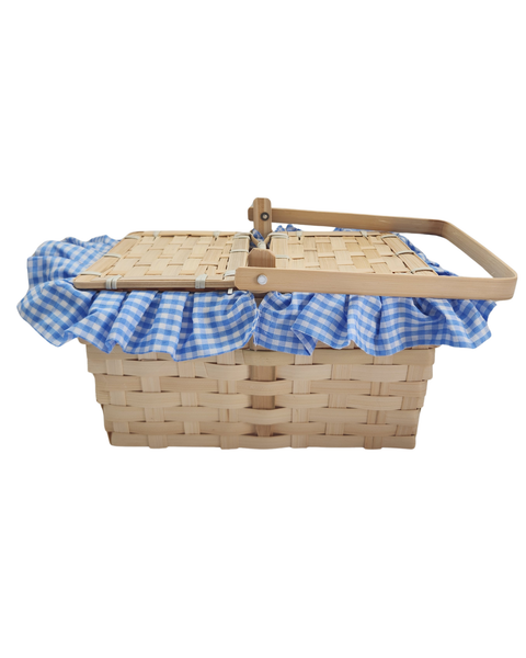 A natural woven wood picnic basket with a matching lid, decorated with a blue and white gingham checkered fabric trim and a wooden carrying handle