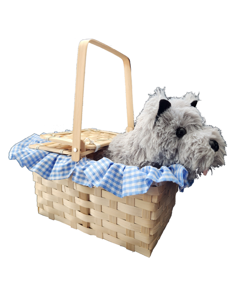 Side view of a woven natural wood picnic basket with a light wood handle, lined with a blue and white gingham fabric liner, and styled with a small gray plush dog