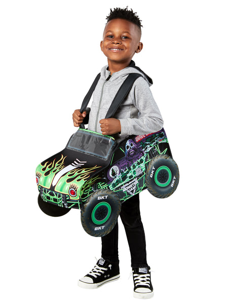 Smiling boy wearing the Toddlers Monster Jam Grave Digger Monster Truck Driver Costume featuring a padded, wearable truck body designed in the shape of the iconic Grave Digger, worn with shoulder straps for a fun “ride‑on” illusion; styled in signature black and purple with bold green flames, skull graphics, and detailed printed panels. Includes oversized foam wheels with green rims, “Monster Jam”/“Grave Digger” branding, and a front windshield graphic for a complete 3D monster truck look