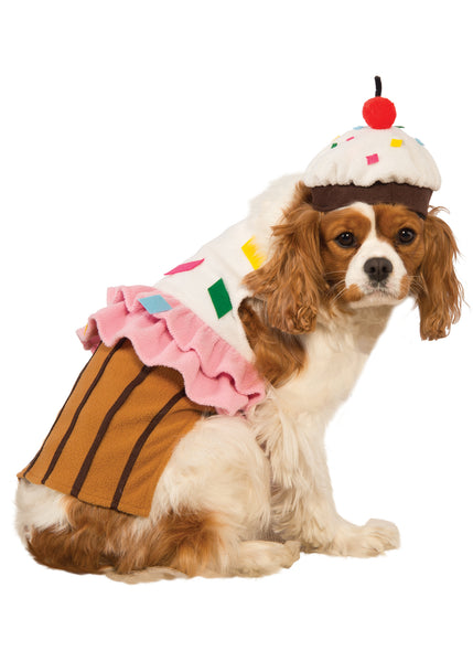 Spaniel wearing the Pets Cute Cupcake Costume featuring a sweet, dessert‑inspired two‑piece outfit with a soft plush body designed to resemble a cupcake base in rich golden‑brown tones with vertical liner striping; topped with a layered “frosting” section made from fluffy white and pink fabric, decorated with colorful sprinkle accents in red, yellow, blue, and green. The look is completed with a matching cupcake headpiece topped with a red pom‑pom cherry detail, adding the perfect finishing touch
