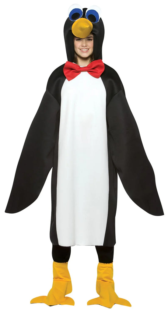 Teenager in the Teens Penguin Costume Featuring a black and white penguin tunic made from lightweight fabric, designed with a white front panel and black back and sides that create a classic penguin color pattern. The costume includes an attached hood with a yellow beak and large stylized eyes, along with a red bow tie at the neckline. The long wing-like sleeves have openings that allow hands to come through, and matching yellow flipper-style shoe covers complete the look.