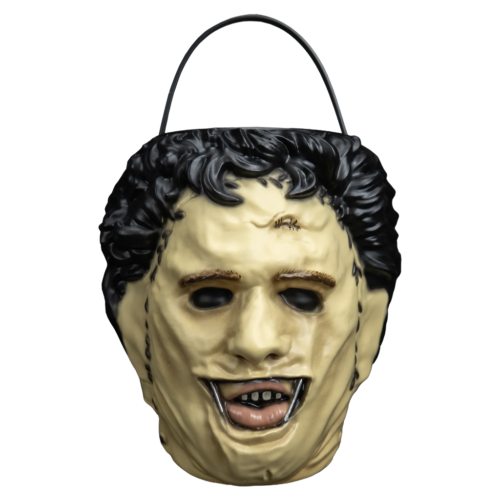 The Texas Chainsaw Massacre Leatherface Candy Treat Pail Bucket
features a molded plastic bucket sculpted to resemble Leatherface’s stitched human‑skin mask, with pale flesh tones, darker seam lines, rough texturing to mimic worn skin, hollow eye holes, a slack unsettling mouth, and an integrated carrying handle, front view