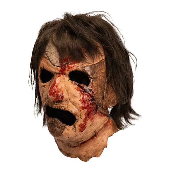 The Texas Chainsaw Massacre 3 III Leatherface Costume Mask of a latex full-head Leatherface mask with grimacing expression, stitched skin details, bloody patches, little rose heart tattoo on the cheek, and attached hair, left side profile