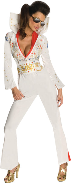 Woman posing in the Womens Deluxe Elvis Presley Aloha from Hawaii Costume which includes a white one‑piece jumpsuit, designed with a dramatic deep V neckline trimmed with the red scarf; embellished across the chest and sleeves with ornate gold, red, and blue jewel‑style accents and star motifs. The jumpsuit is finished with long fitted sleeves that flare slightly at the cuffs, a wide gold decorative belt motif, and structured pant legs that fall into bell‑bottom shape