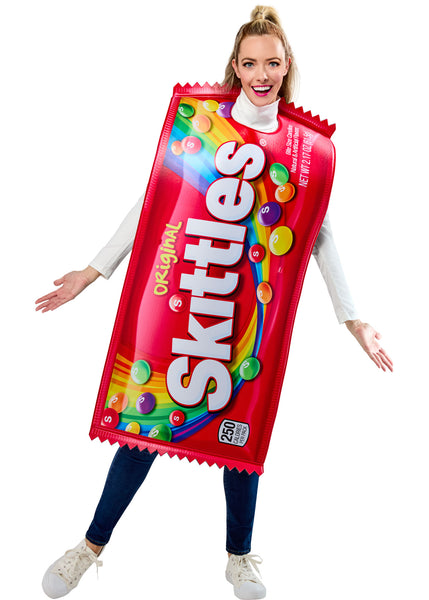 Woman in the Adults Skittles Candy Costume Featuring a foam-backed tunic costume designed to resemble a Skittles candy bag, with a bright red wrapper print, bold white Skittles logo across the front, a rainbow graphic cascading down the design, scattered multicolored candy pieces with S markings, zigzag wrapper-edge detailing at the top and bottom, and a sleeveless pull-on style with side ties for an adjustable and comfortable fit.